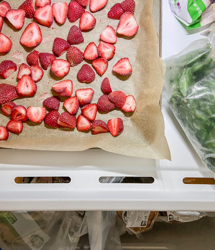 fresh frozen strawberries on a cookie sheet in freezer