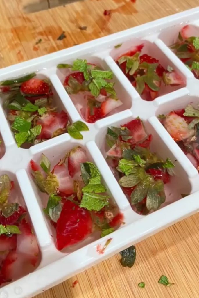 ice cube tray filled with strawberries and mint 