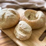 loaves of bread cut into bread bowls placed on a cutting board