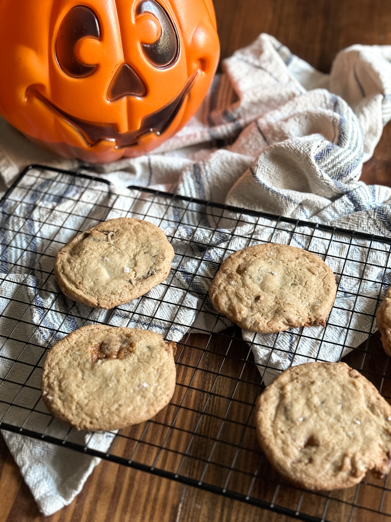 cookies on a cooling rack next to a halloween candy bucket