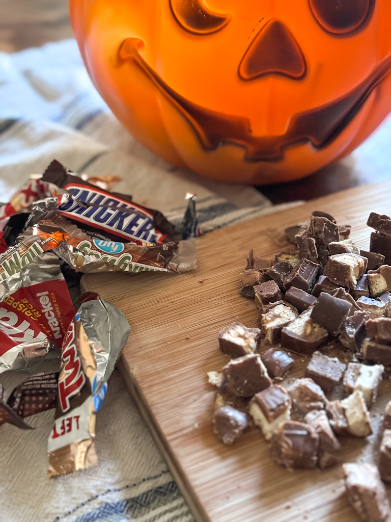 chopped halloween candy on a cutting board next to candy wrappers