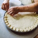 Person Pinching Round Pie Dough on Grey Tray