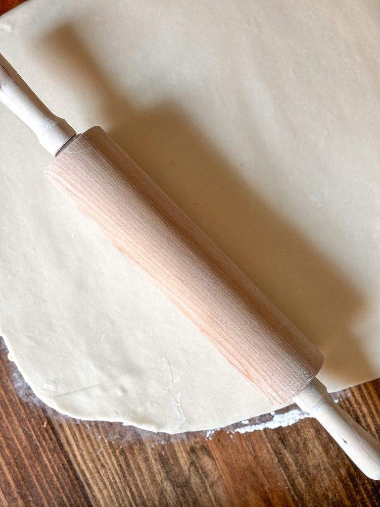 dough rolled out on a table with a wooden rolling pin on top