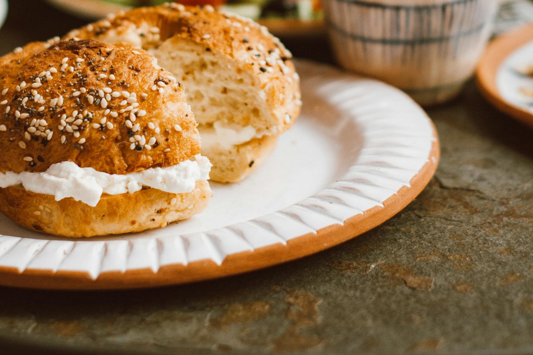 A cozy breakfast setting featuring a cream cheese bagel with a cup of coffee, perfect for a relaxing morning.