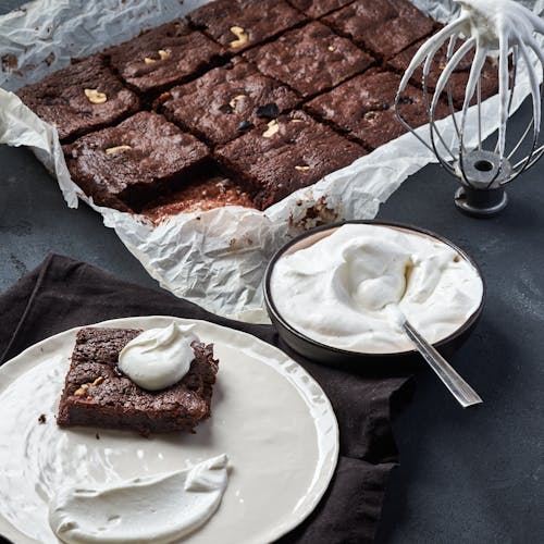 Mouth-watering brownie served with whipped cream, perfect for dessert lovers.