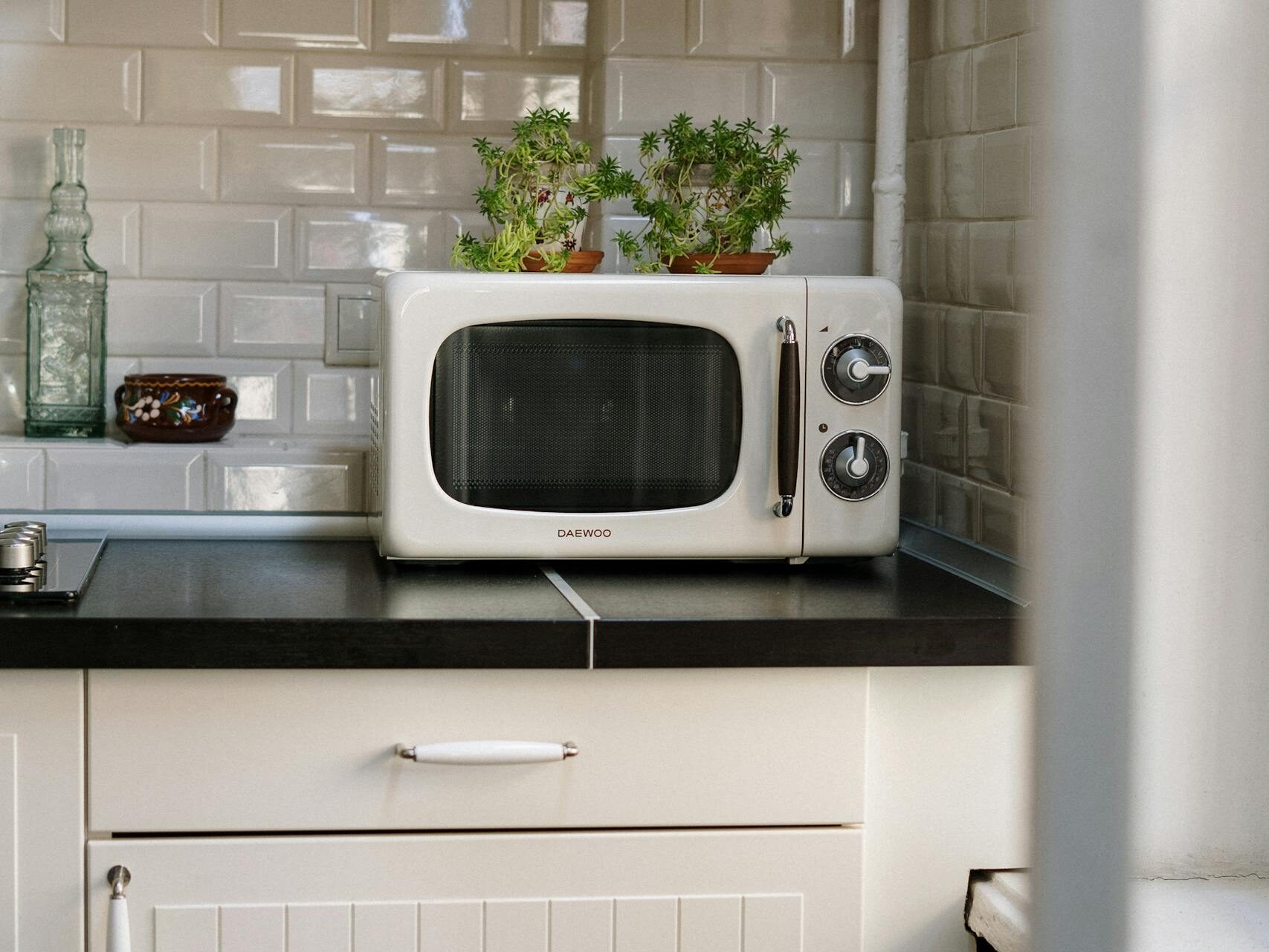 A cozy retro kitchen featuring a white vintage microwave and potted plants.