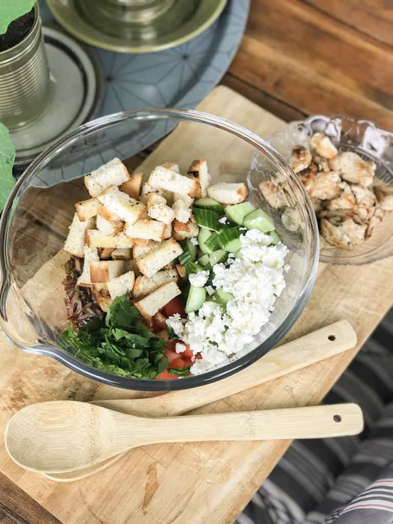 Top view of a fresh vegetable salad with croutons in a glass bowl on a wooden board.