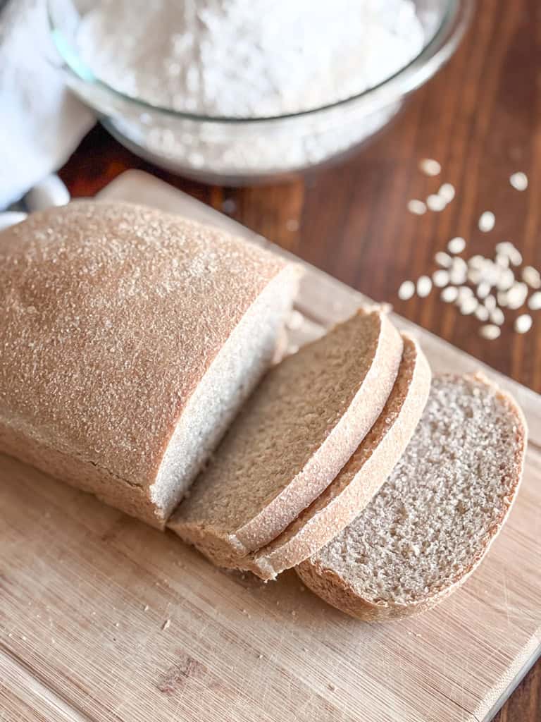 overhead view of a loaf of freshly milled sourdough sandwich bread with a bowl of flour