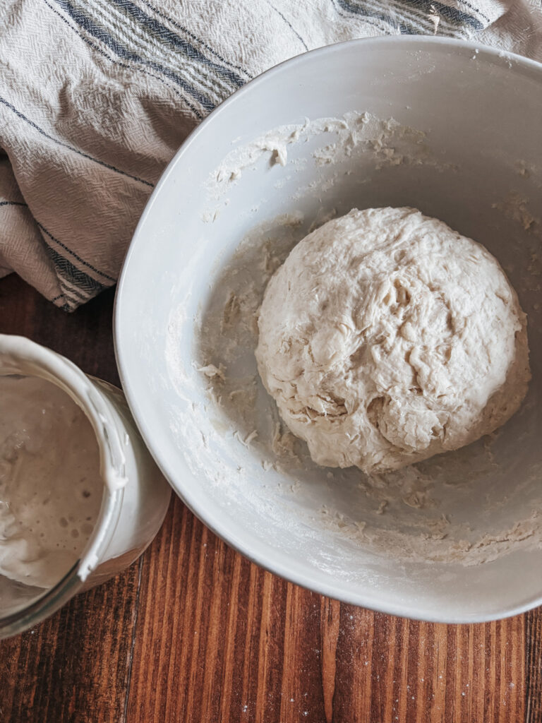 bowl of pizza dough next to a jar of sourdough discard