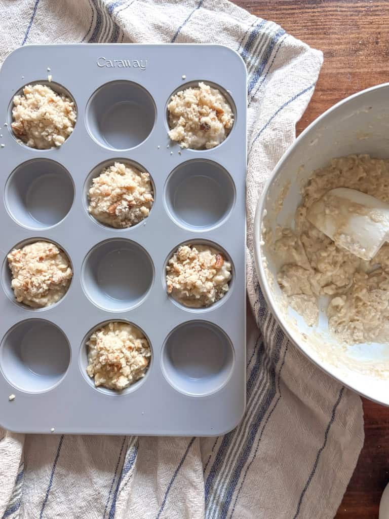 bowl of sourdough muffin batter next to a muffin pan filled with batter