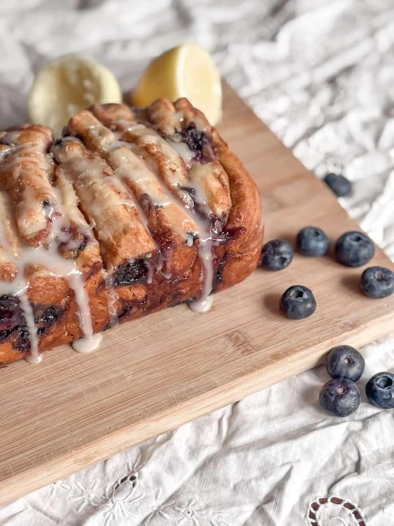 sourdough blueberry bread on a cutting board with blueberries