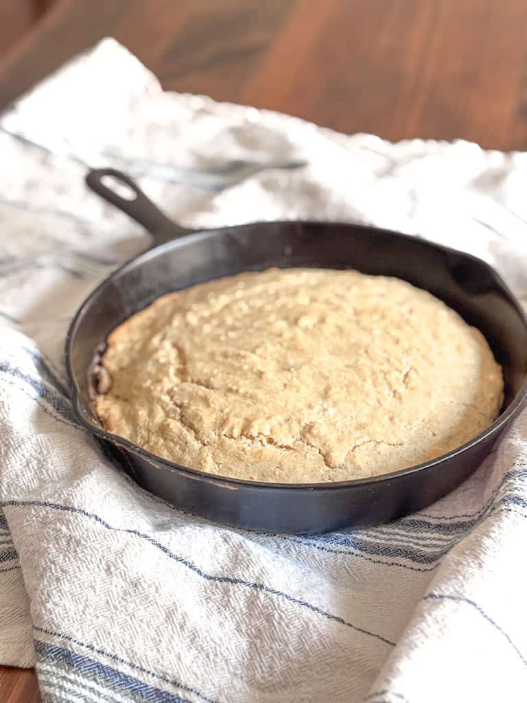 cake of sourdough cornbread in a skillet on a hand towel