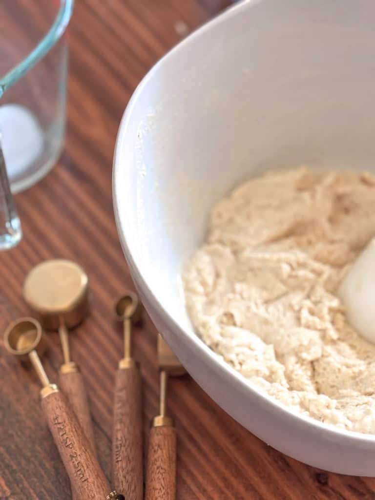 bowl of sourdough cornbread batter with measuring spoons close by