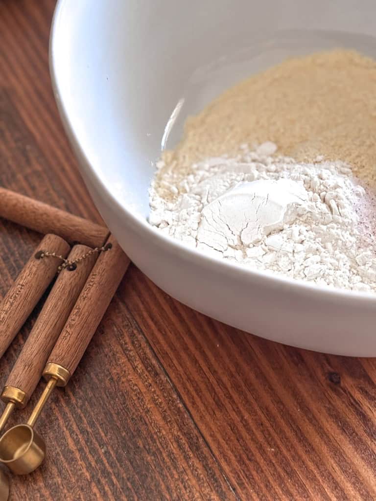 mixing bowl with dry ingredients for sourdough cornbread with measuring spoons close by