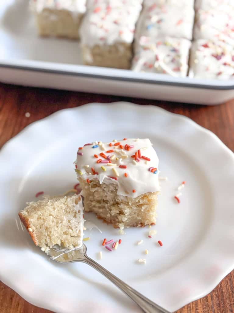 a small square of cake on a white plate with a small bite on a fork