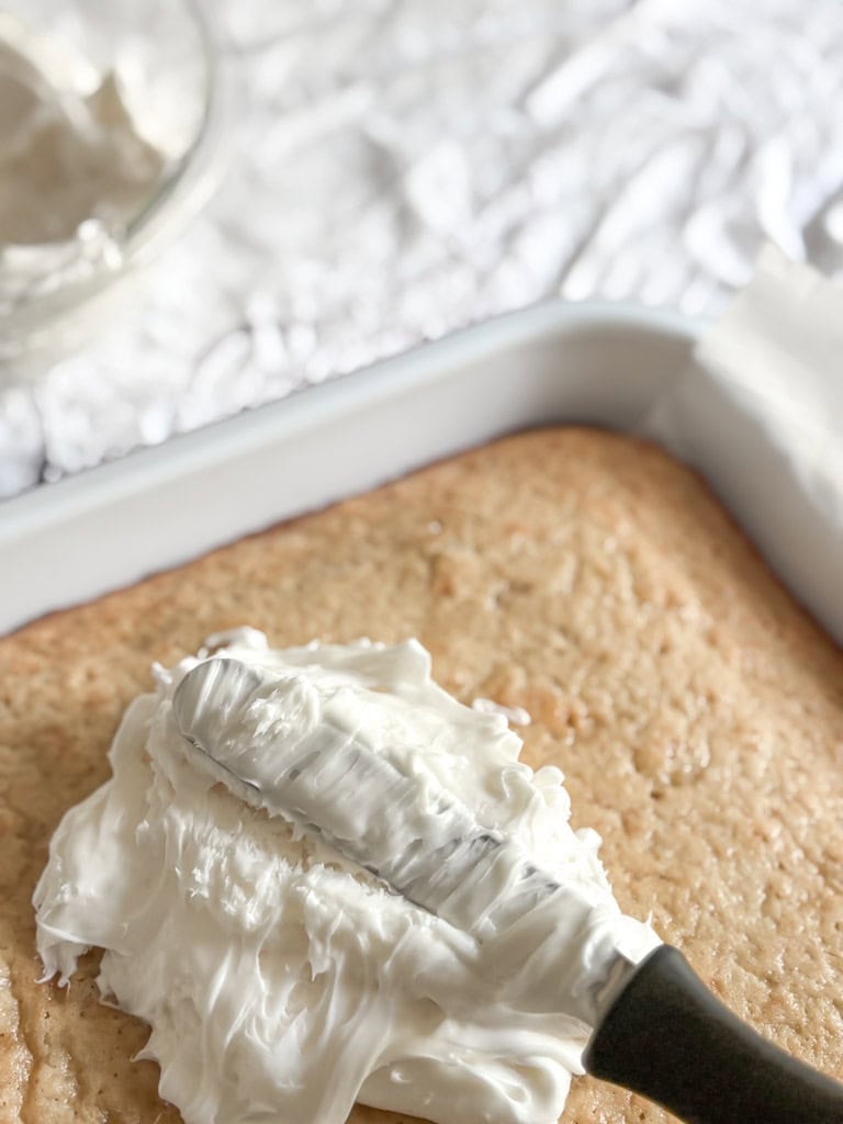 sheet cake being frosted with white frosting