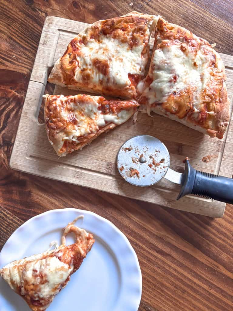 plice of deep dish pizza on a plate beside a cutting board and pizza cutter