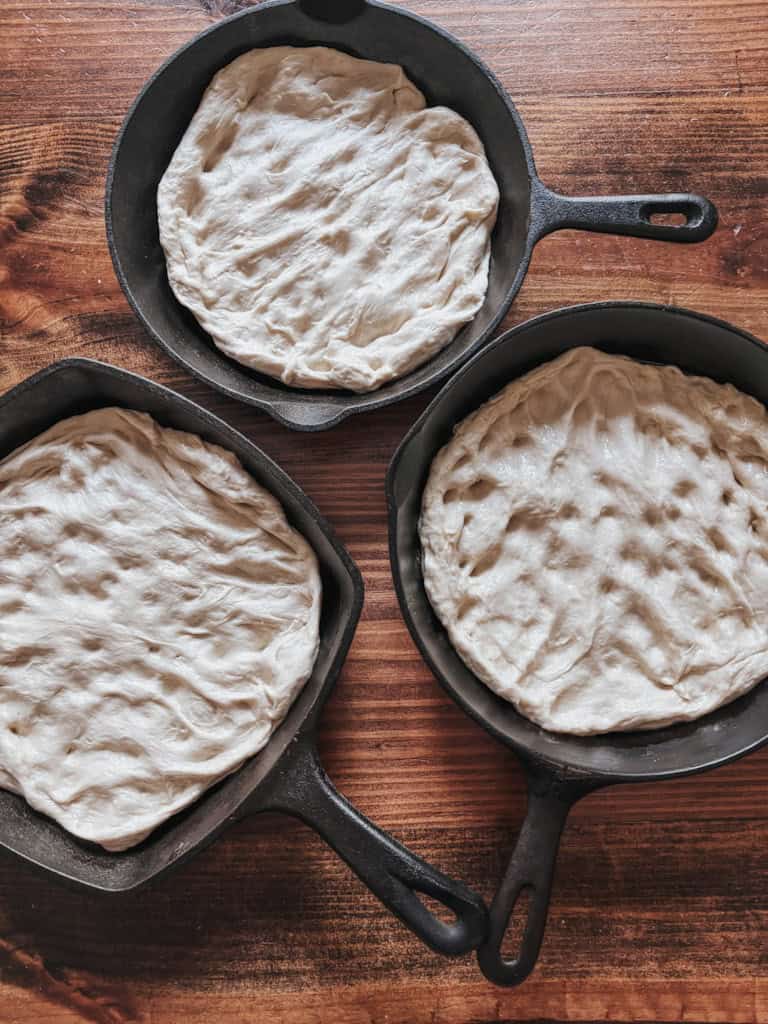 3 cast iron skillets with deep dish pizza dough