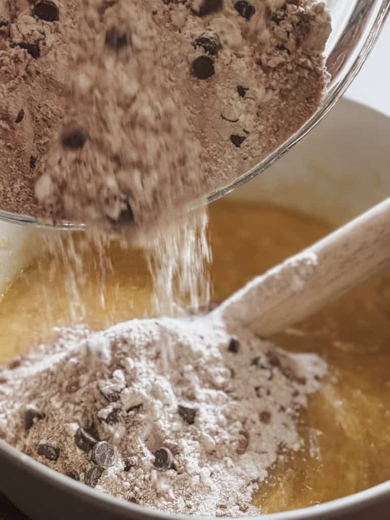 dry brownie mix being poured into wet brownie mix
