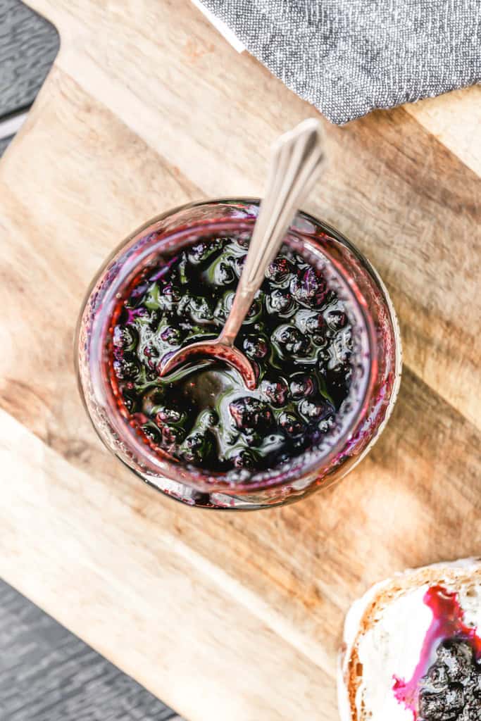 top view of an open jar of blueberry jam with a spoon