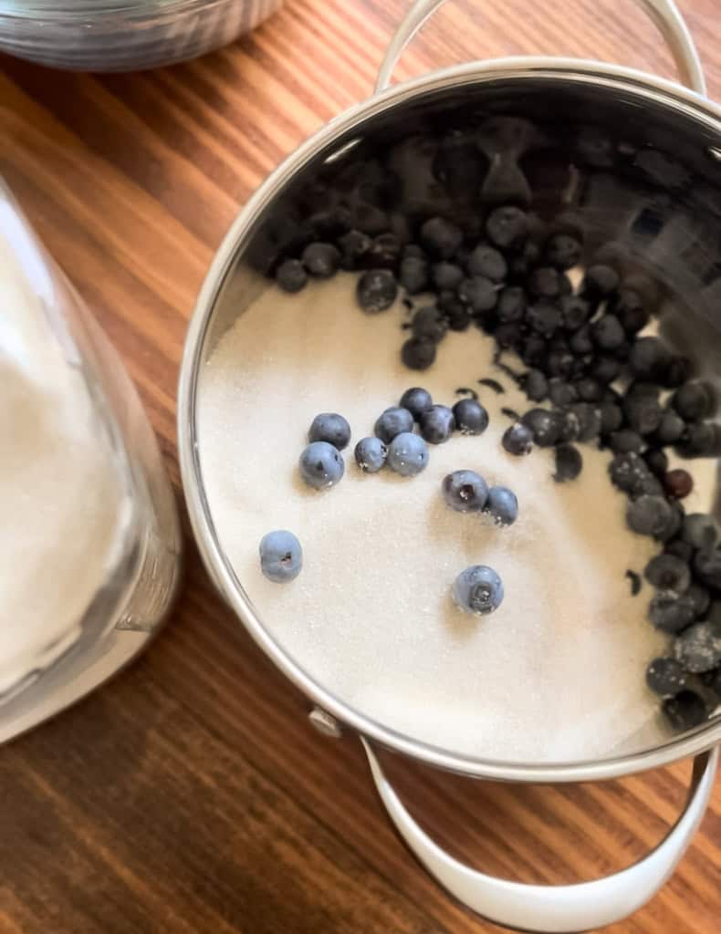 top view of a pot of blueberries and sugar on a table
