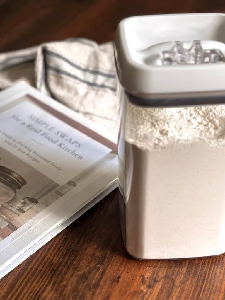 container of pancake mix on a table next to a notebook