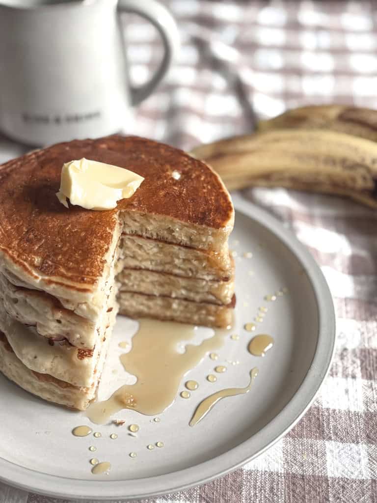 stack of sourdough banana pancakes on a plate with syrup and butter on top