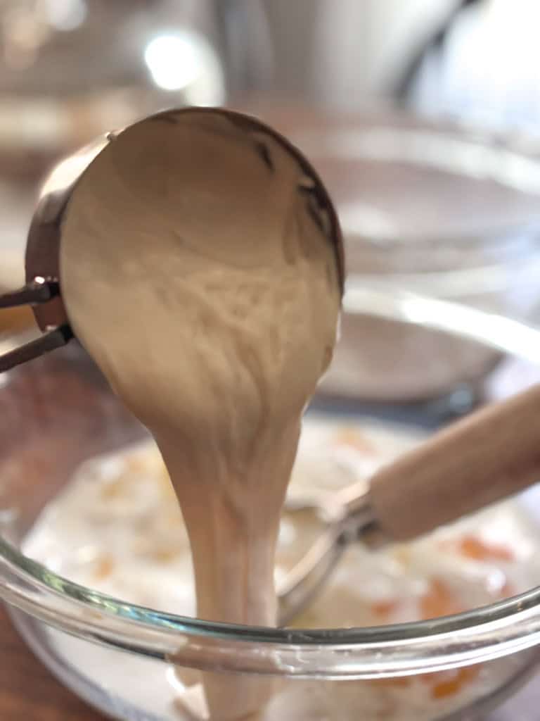 sourdough discard being poured into a bowl from a measuring cup