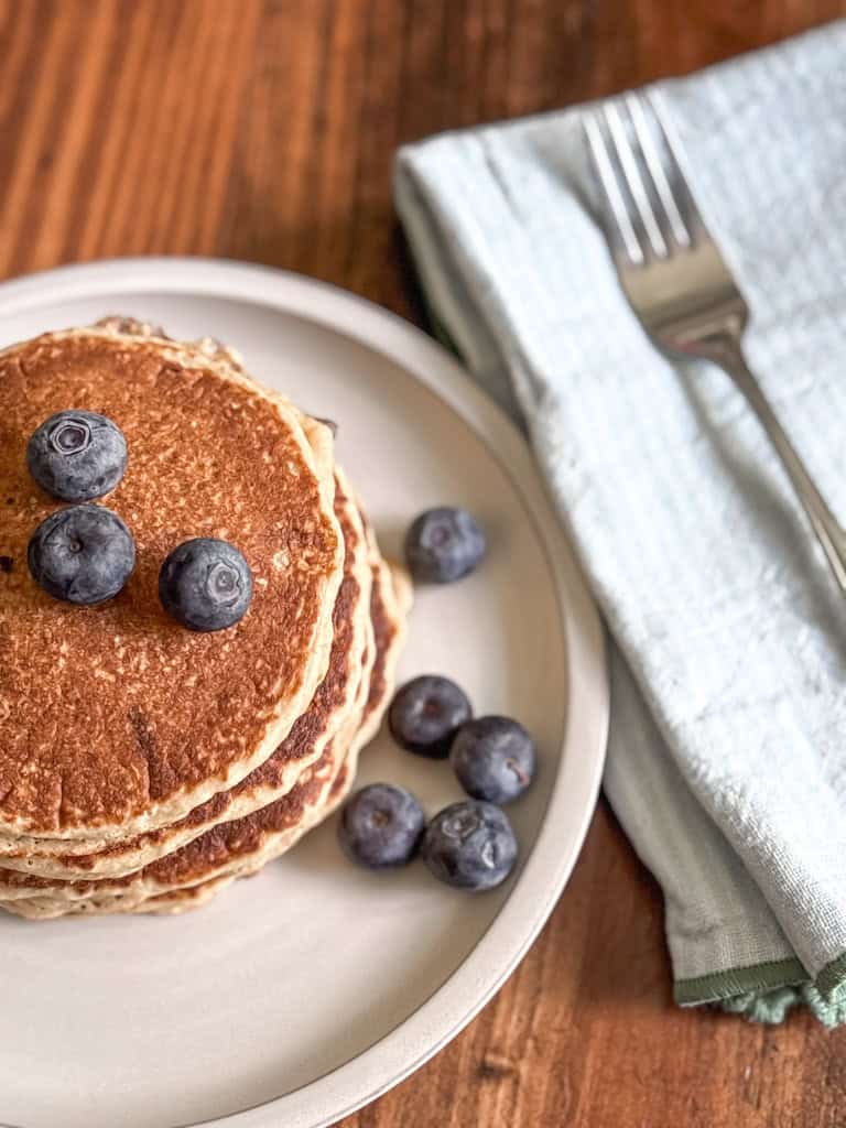 stack of whole wheat pancakes made with fresh milled flour on a plate with blueberries