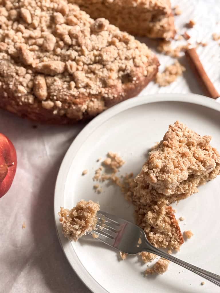 slice of apple cake on a plate with a bite on a fork